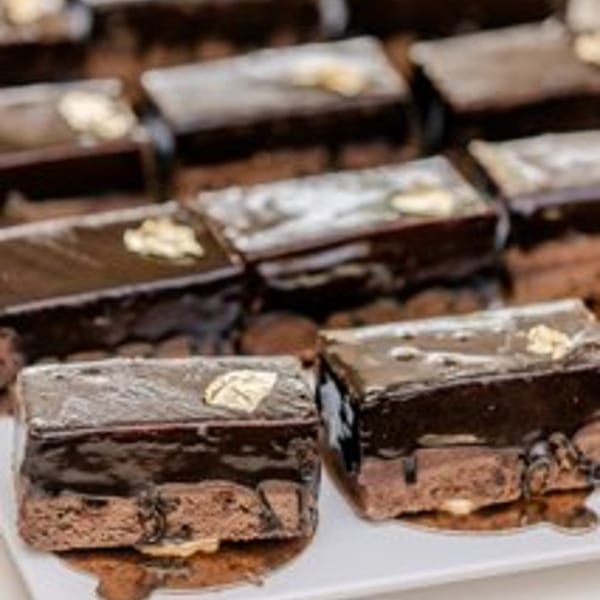 Rows of rectangular chocolate cakes with gold leaf on top, displayed at Alexandria Pastry Shop.